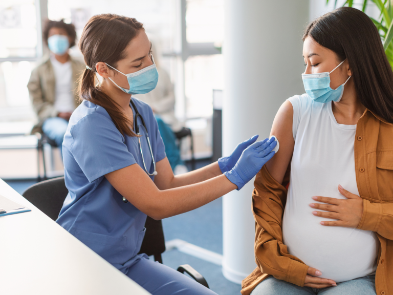 Healthcare worker administering a vaccine to a pregnant woman during a maternal immunization appointment