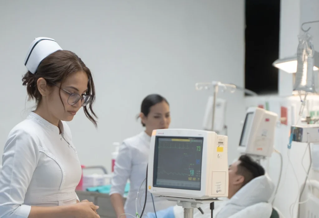 Nurse monitoring a patient and reviewing vital signs in a hospital setting