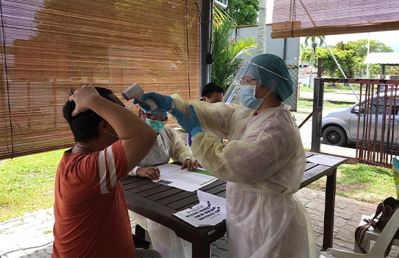 Health worker in protective gear preparing to vaccinate a man at an outdoor clinic