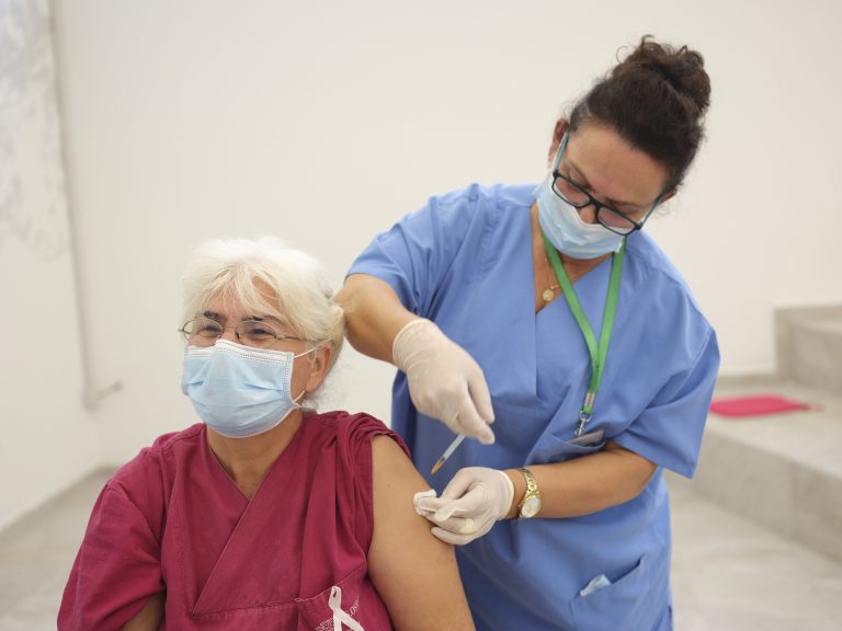 health worker administering vaccine to elderly woman